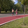 Young running couple jogging on asphalt road in park